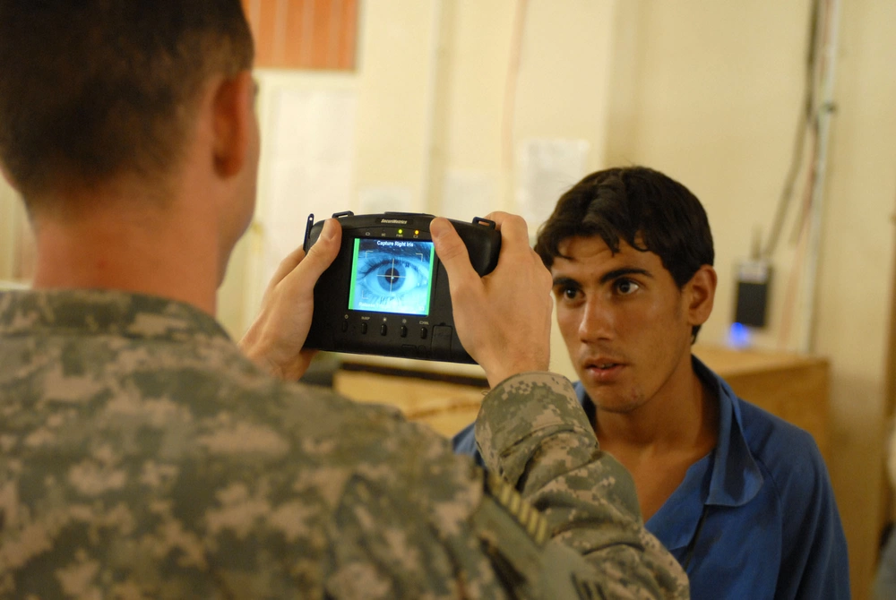 US Army soldier uses a biometrics camera to capture iris biometrics data on workers at a forward operating base in northern Baghdad.
