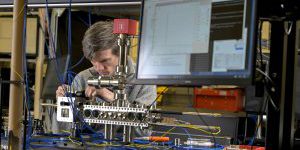 research physicist from the U.S. Naval Research Laboratory (NRL) Quantum Optics Section attaches fiber-optic cables to deliver light into the compact laser-delivery system
