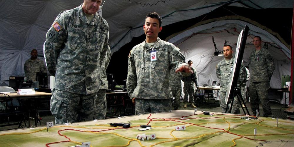 Military personnel conversing near a terrain model.